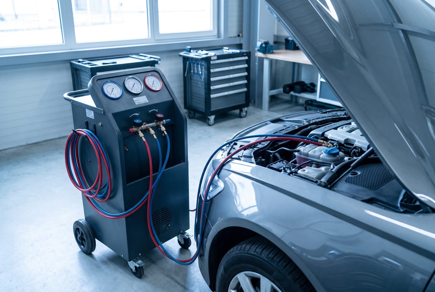 Klimaservicegerät ist an den geöffneten Motorraum eines Fahrzeugs angeschlossen.